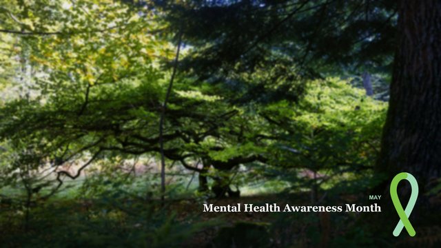 Forest photo background with the words Mental Health Awareness Month and a green ribbon
